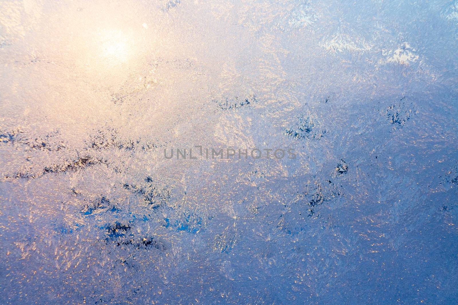 Nature background with ice pattern and sunlight on winter window.