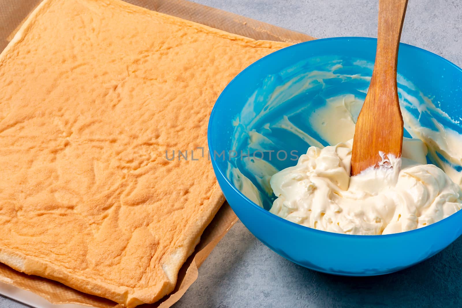 Smearing a baked roll cake with whipped butter cream.