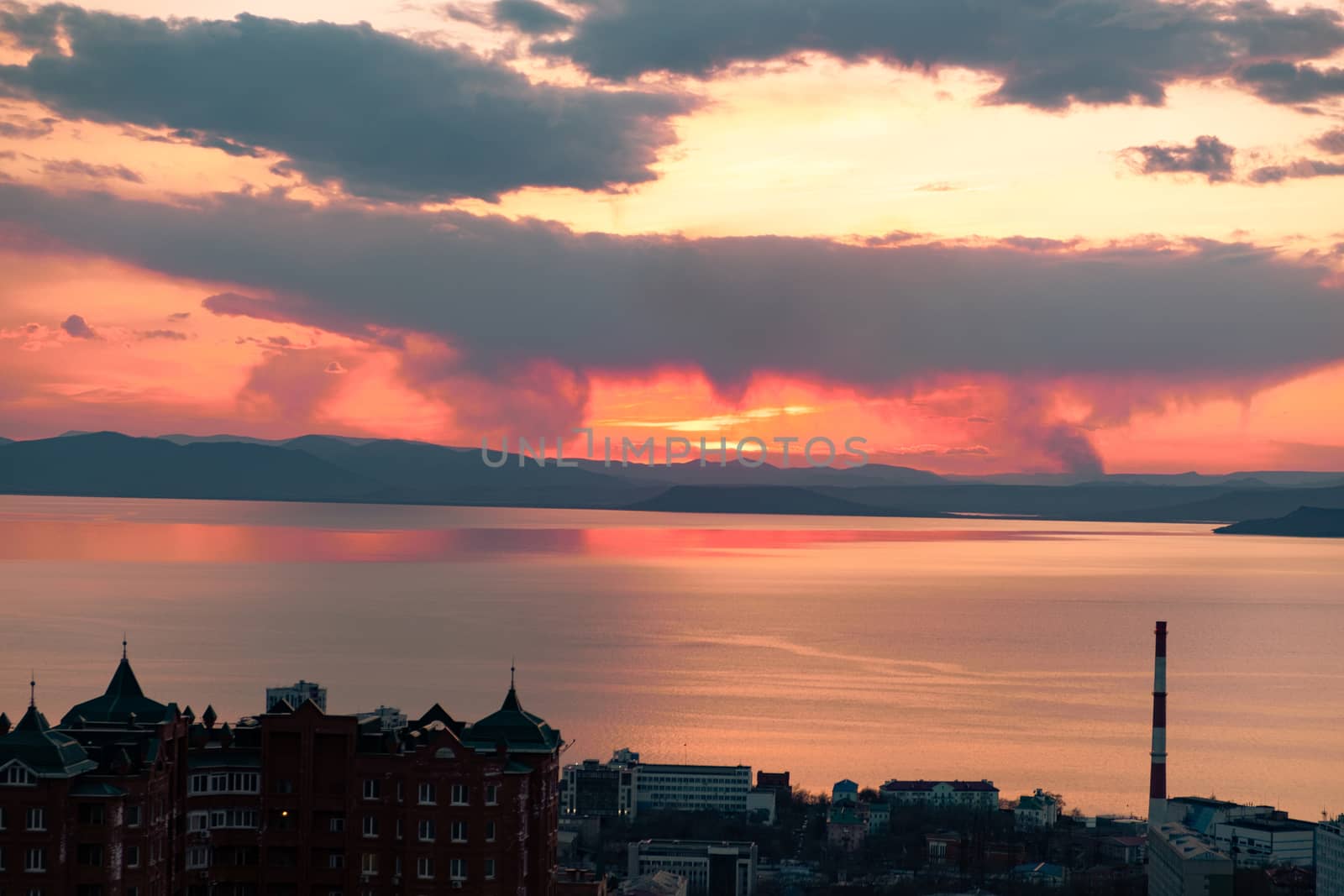 View of the city of Vladivostok from the hill eagle's nest . Sunset. The sky is orange and pink. Sea and city at sunset.