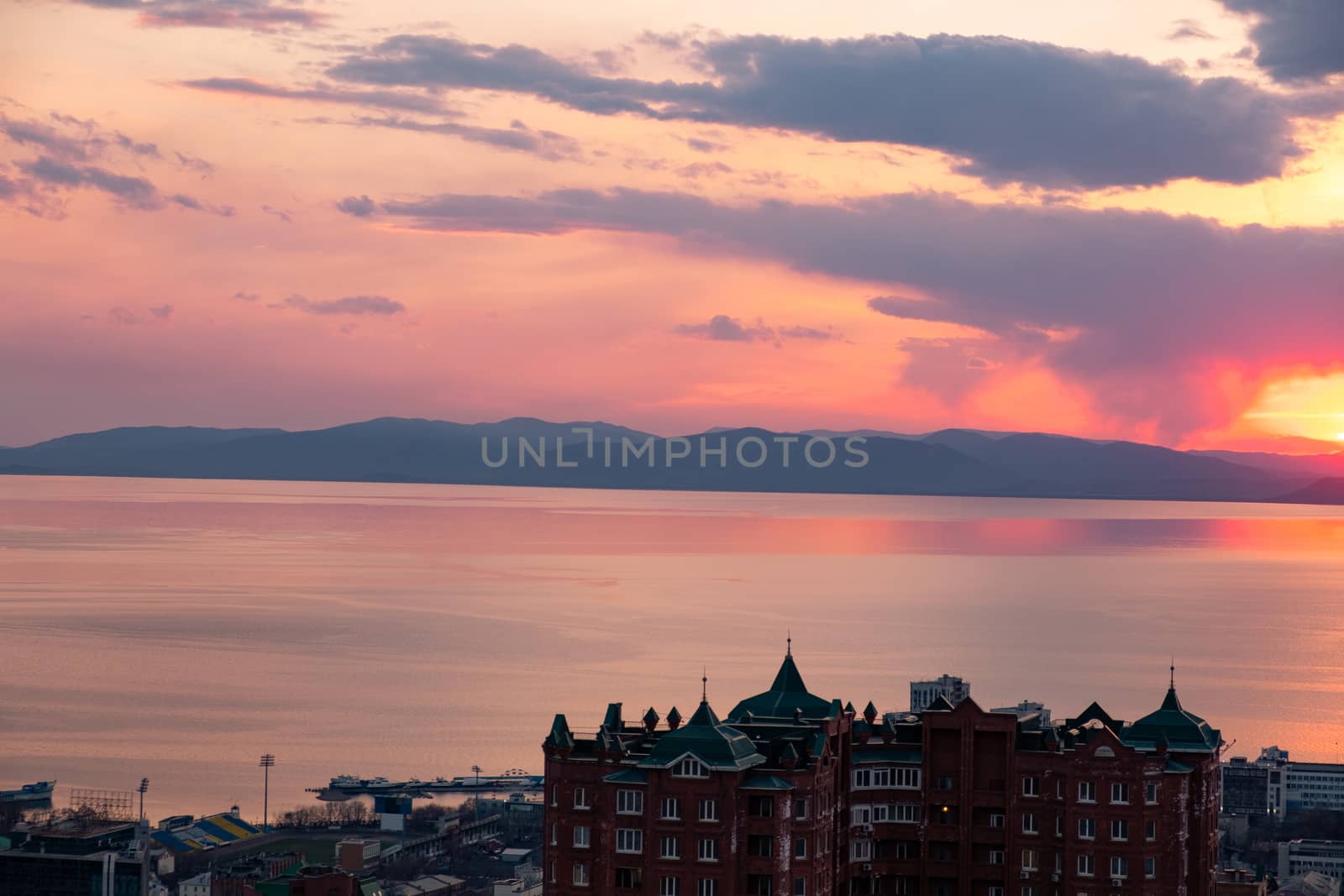 View of the city of Vladivostok from the hill eagle's nest . Sunset. The sky is orange and pink. Sea and city at sunset.