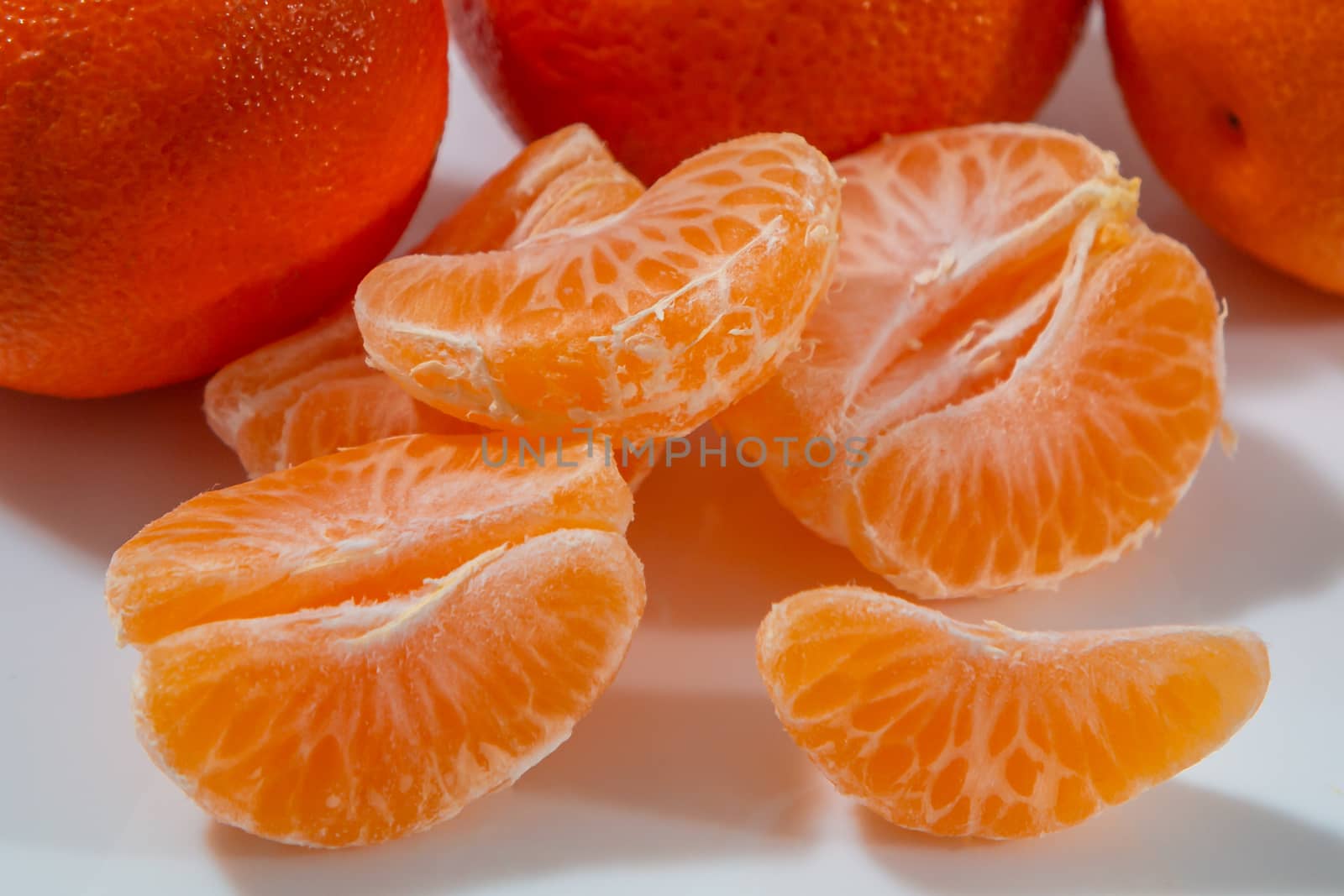 Several whole and peeled ripe tangerines on a white plate.