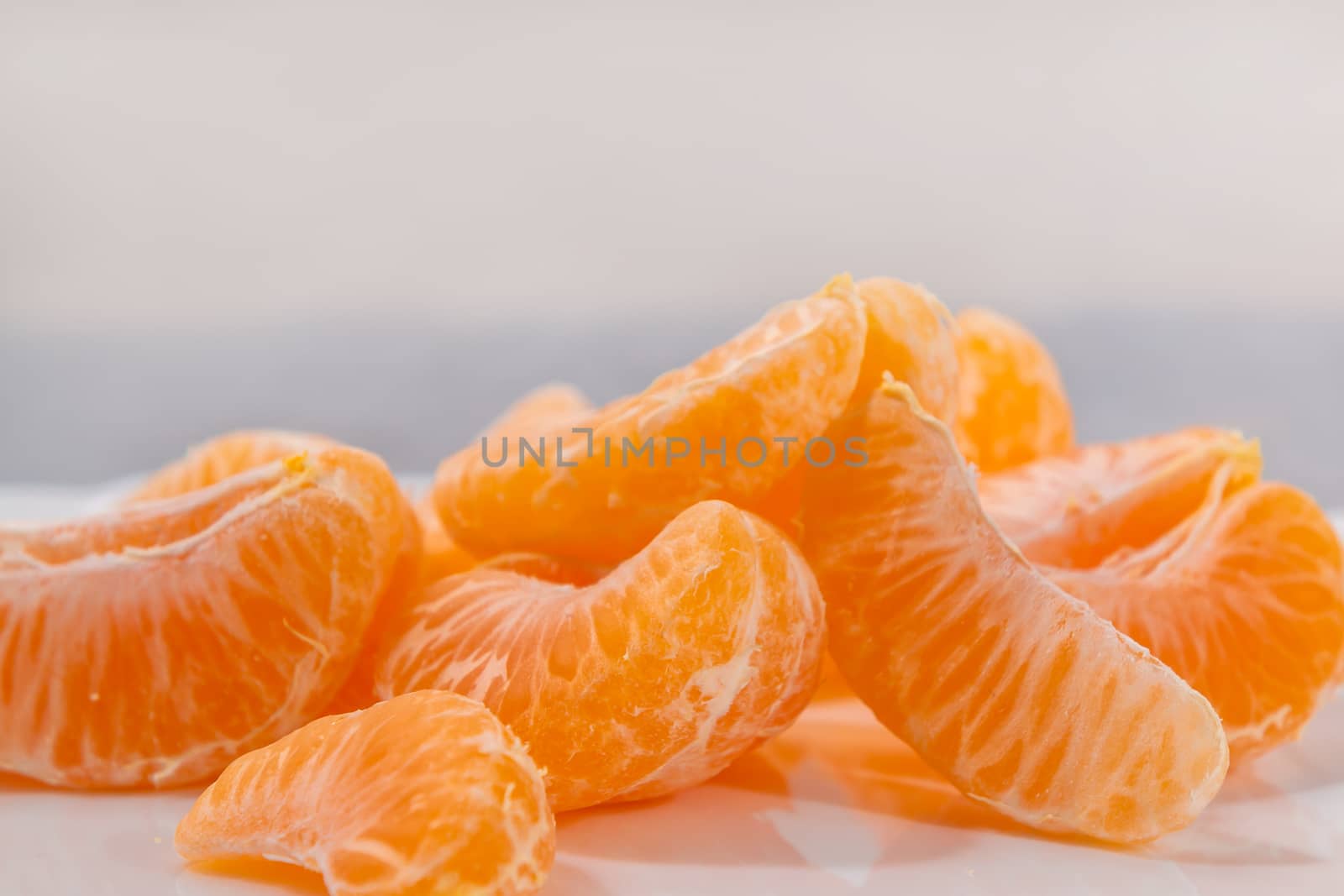 few peeled tangerine slices on the grey surface of the table, space for text.