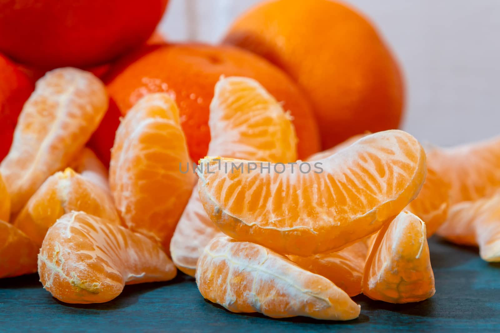 few peeled tangerine slices on the turquoise surface of the table, space for text.