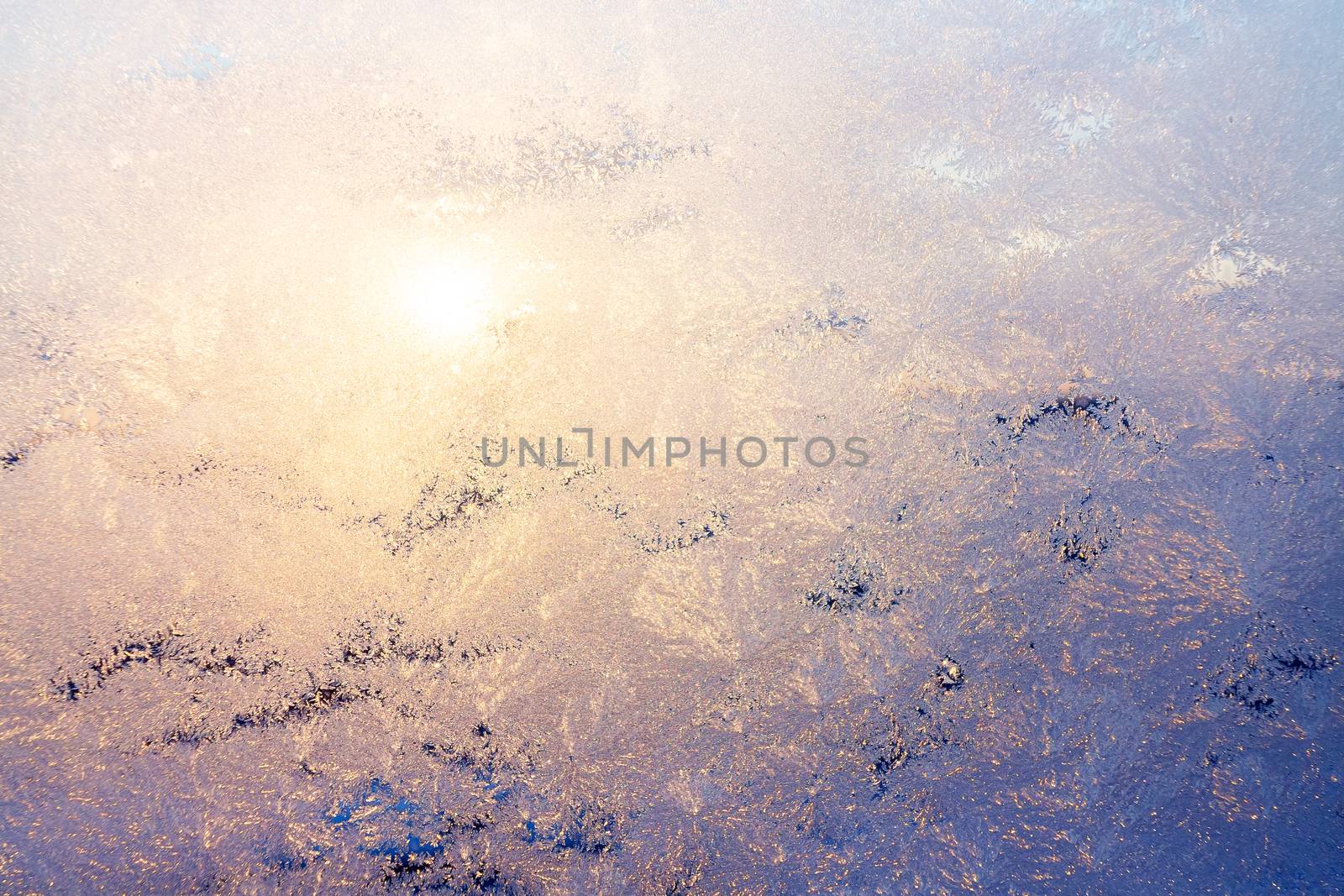 Nature background with ice pattern and sunlight on winter window.