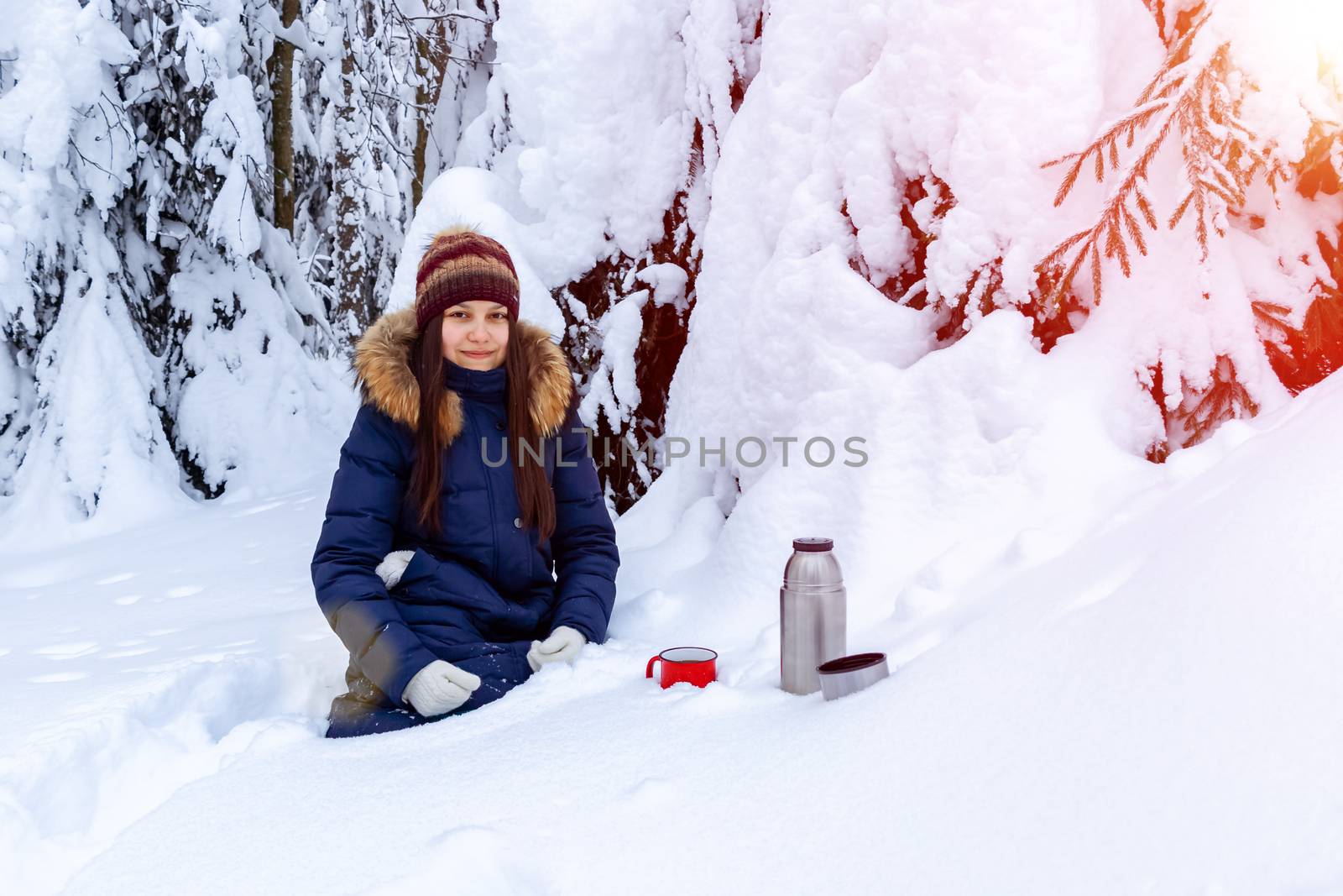 girl drinks coffee from a thermos while walking through a snowy winter forest by galsand