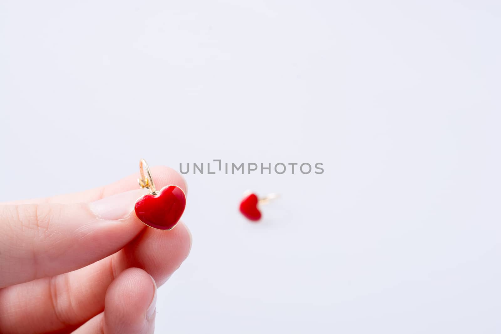 Heart shaped earring in hand on white by berkay