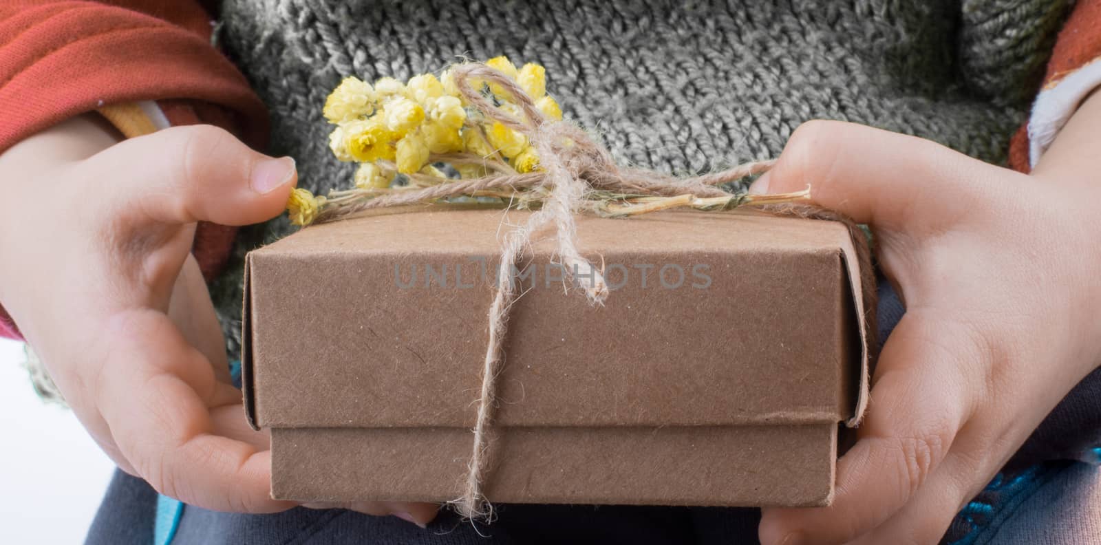 Baby holding a wrapped gift box with yellow flower on white background