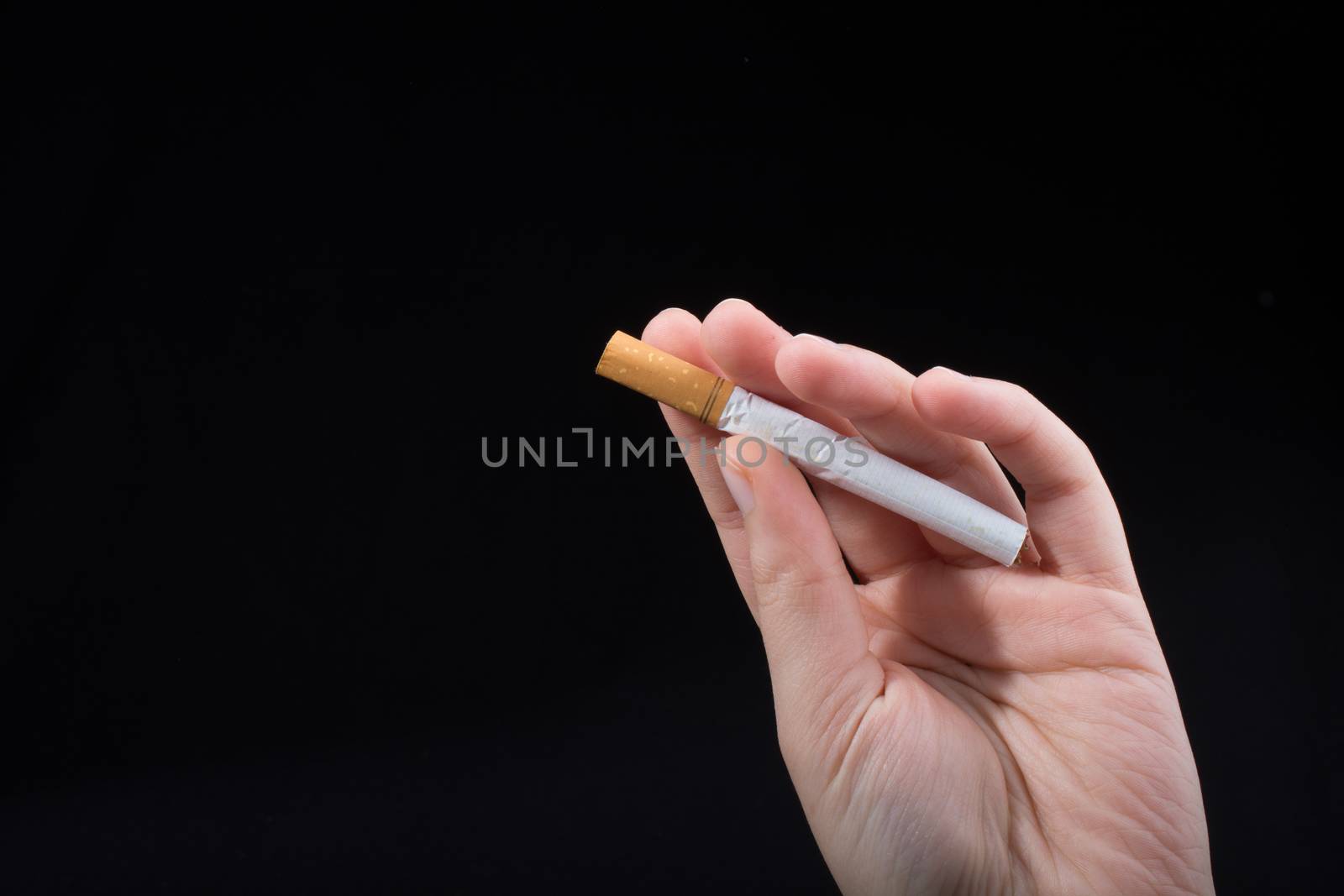 Hand is holding a cigarette on black background