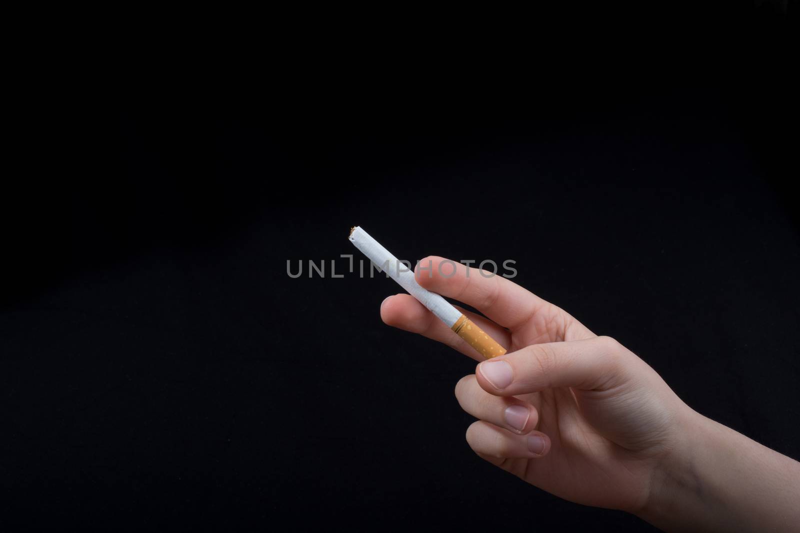 Hand is holding a cigarette on black background