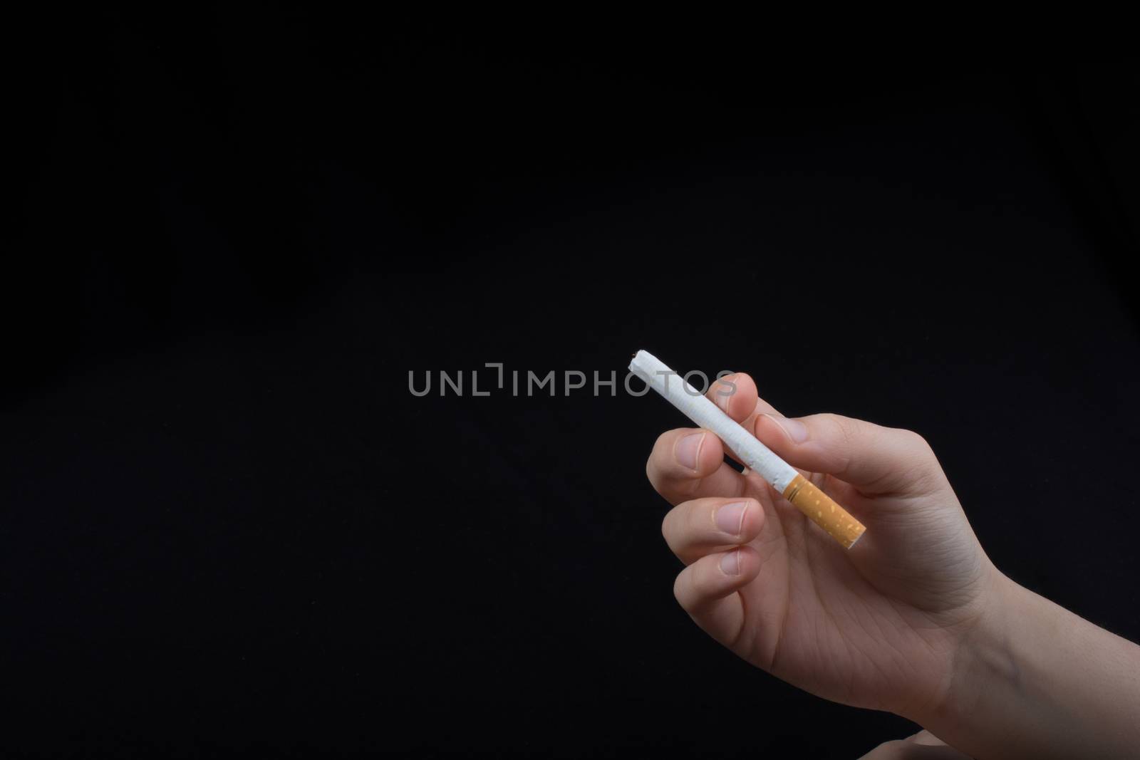 Hand is holding a cigarette on black background