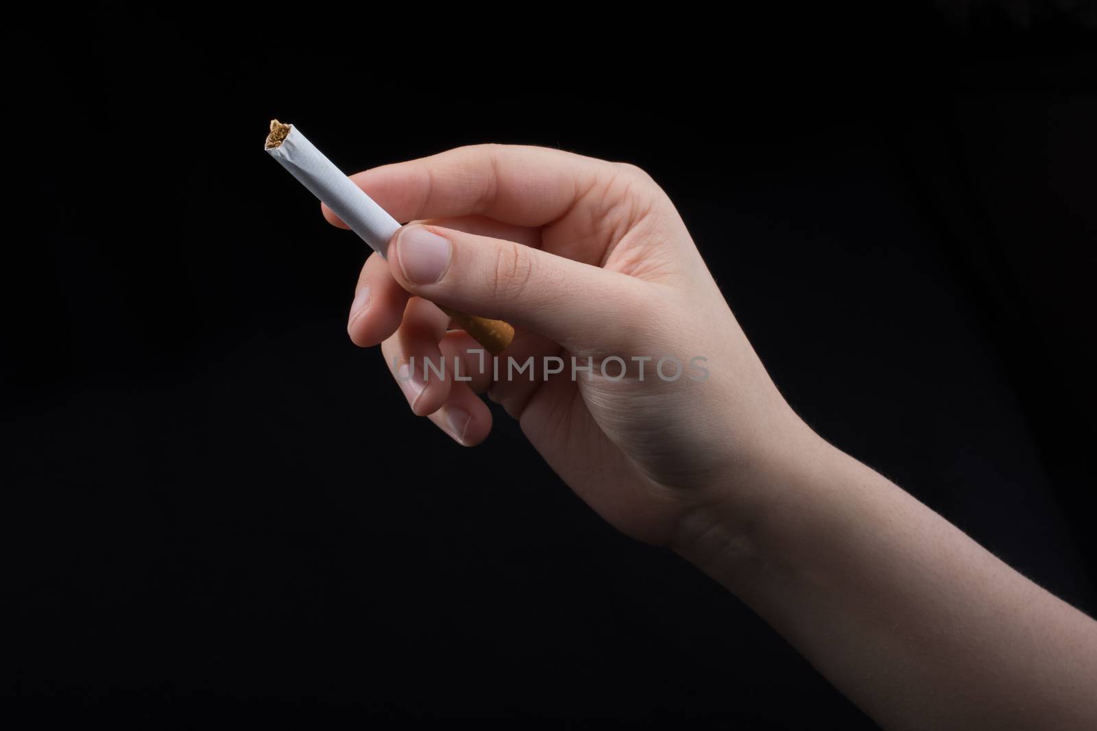 Hand is holding a cigarette on black background