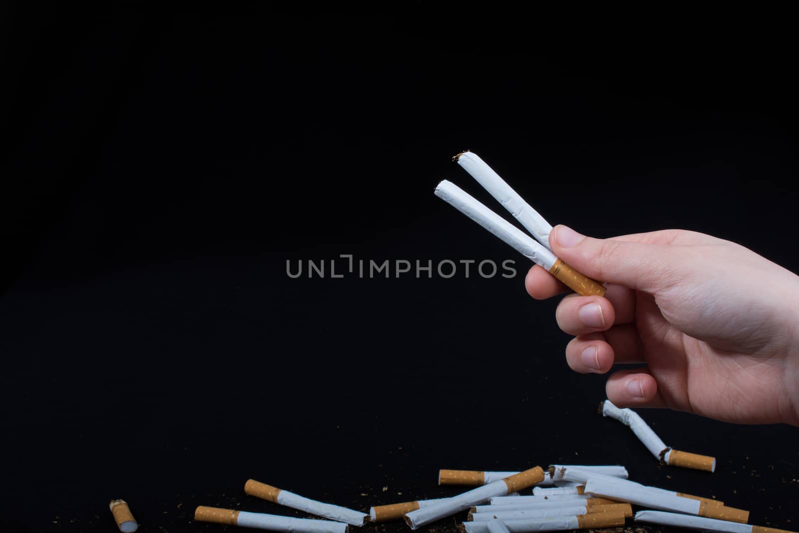 Hand is holding cigarettes on a black background
