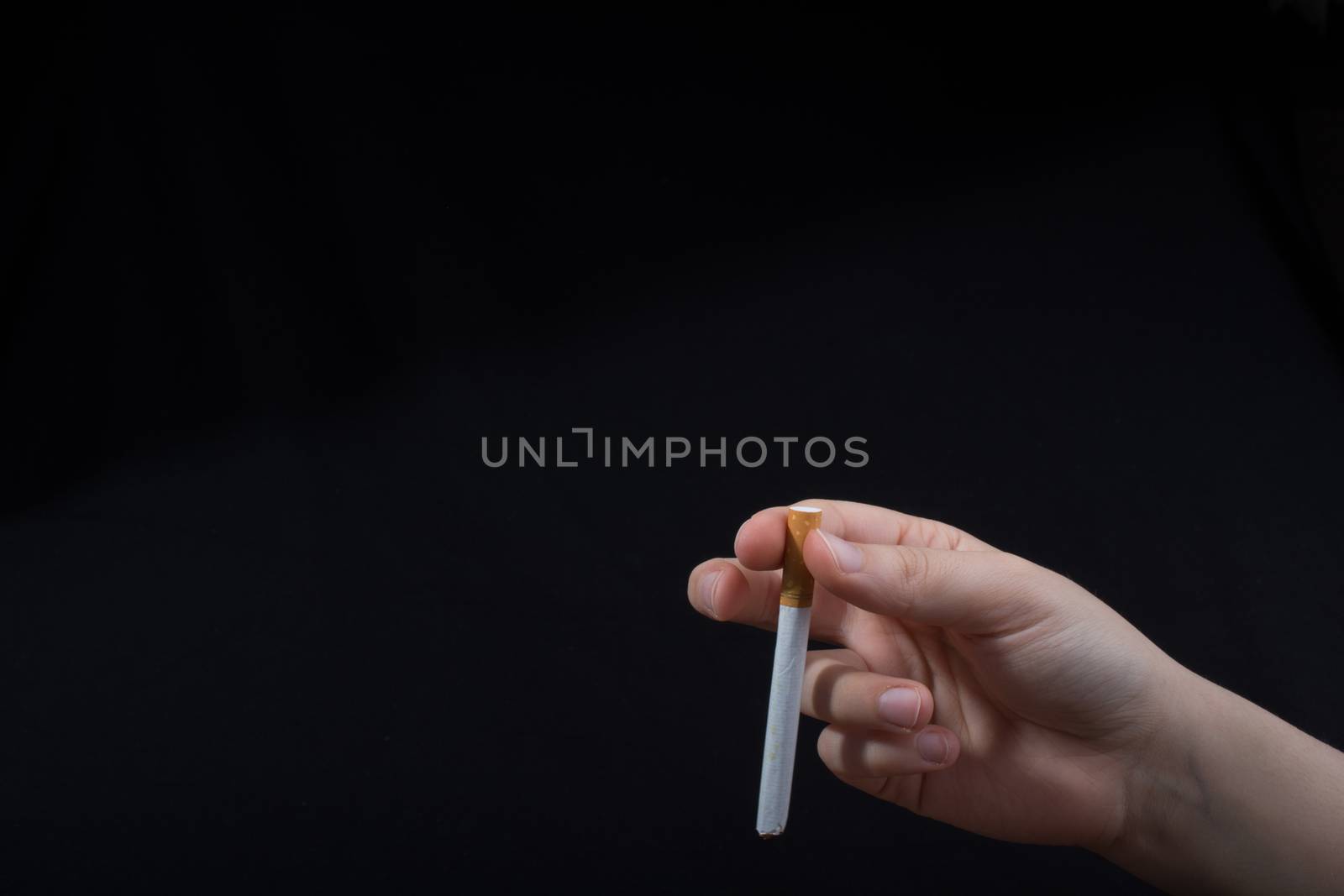 Hand is holding a cigarette on black background