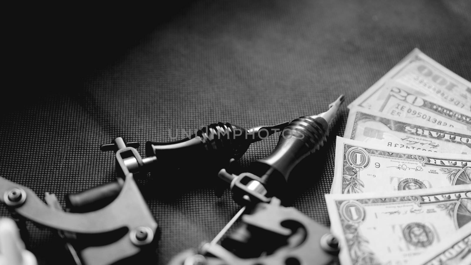 Tattoo machines on a black background and dollars. Tattoo art concept. Money for tattoo