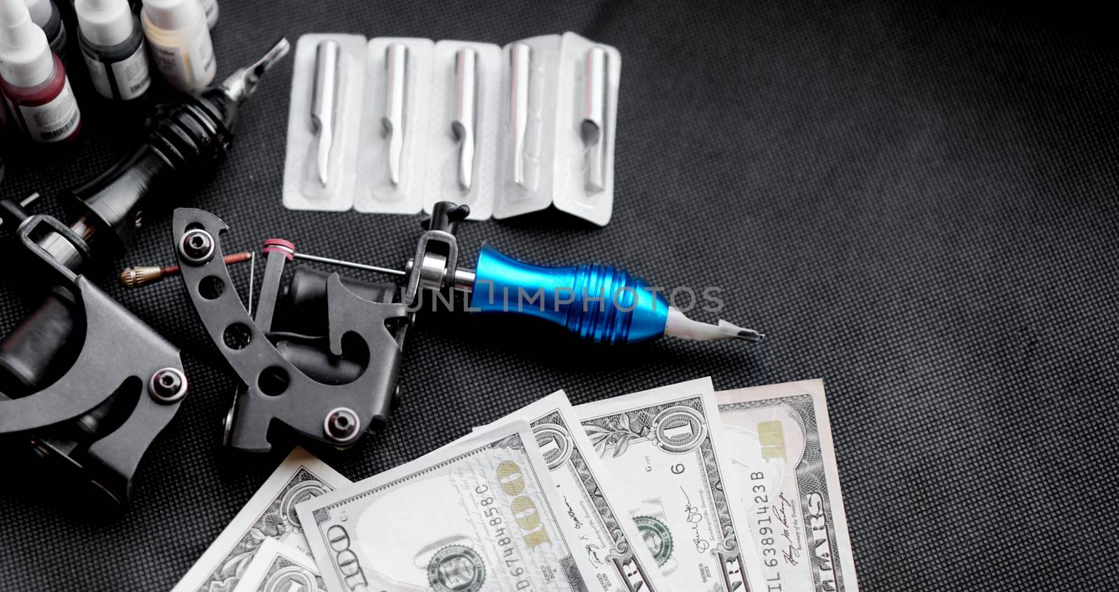 Tattoo machines on a black background and dollars. Tattoo art concept by natali_brill