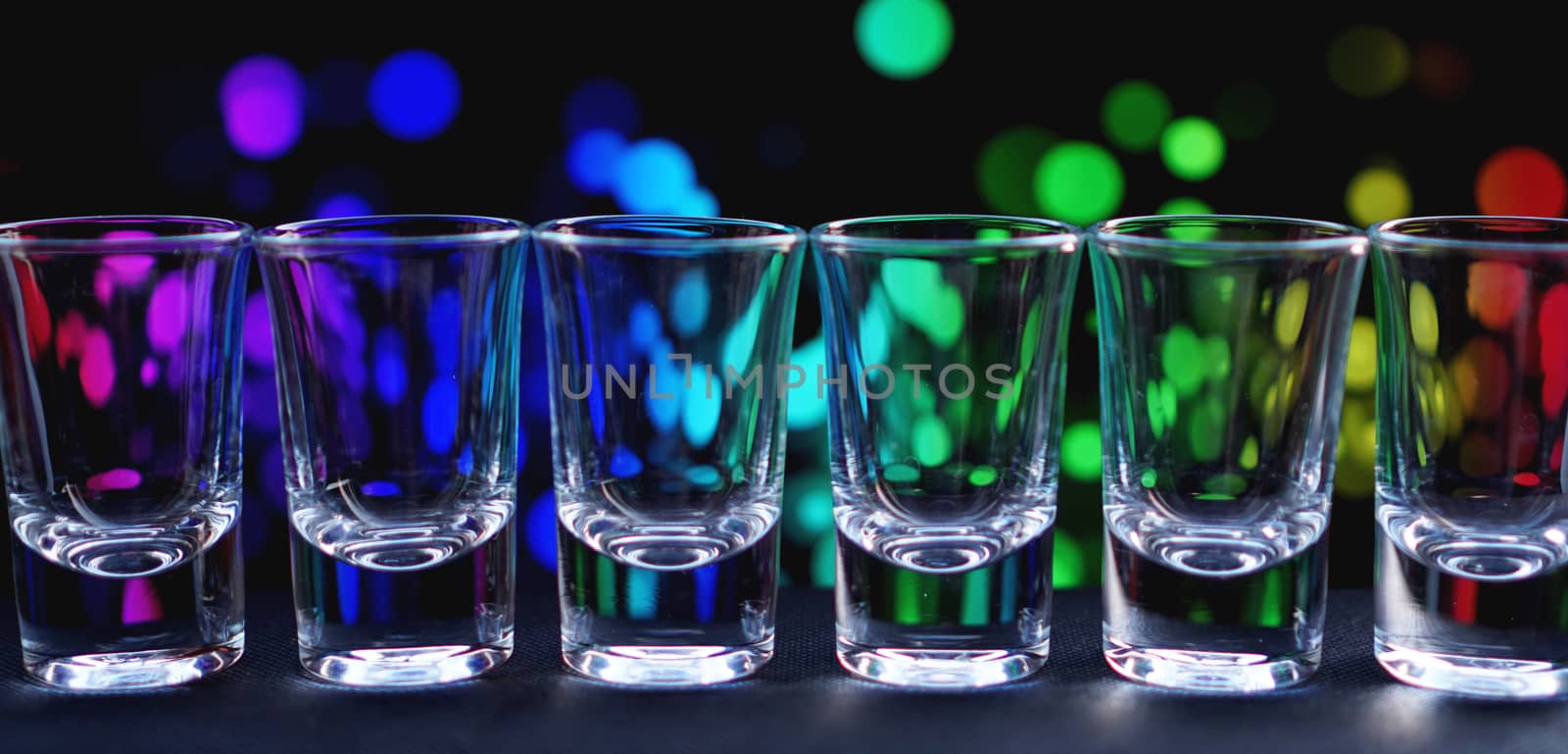 Row of clean shiny glasses lined up on a bar counter in a nightclub ready for the barmen to use to serve alcoholic beverages