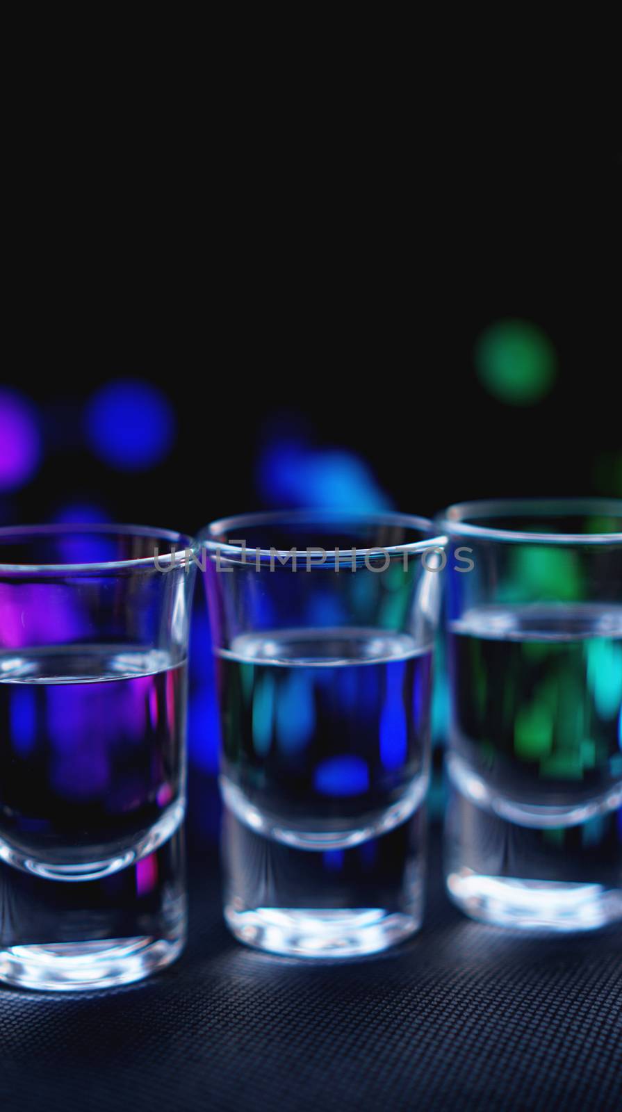 Glasses of vodka or tequila. In bar - neon background