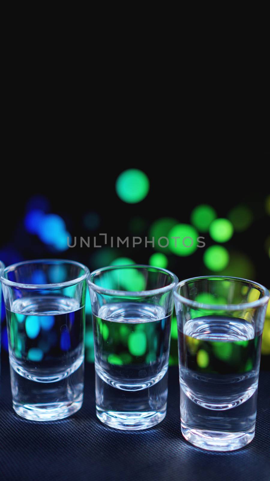 Glasses of vodka or tequila. In bar - neon background