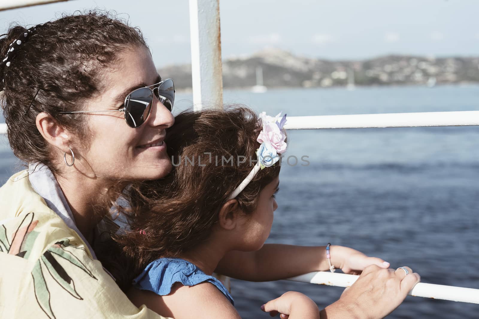 portrait of a mother and daughter looking through the railing of a boat, La Maddalena, Sardinia, Italy