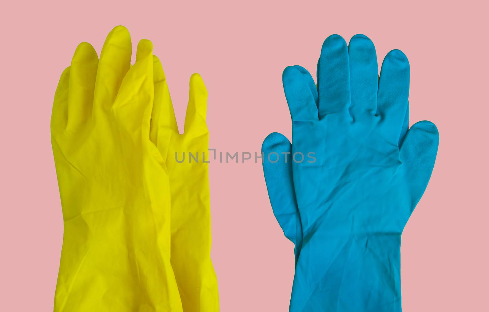 Top view of yellow and blue rubber protective gloves on pink table for spring or daily cleaning. The concept of a commercial cleaning company