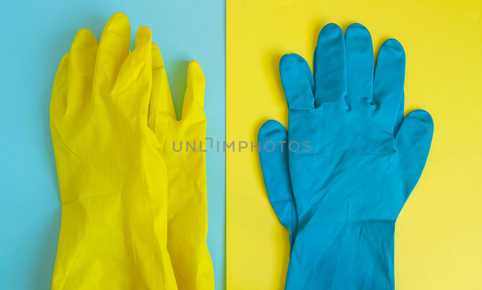 Flat lay of yellow and blue rubber protective gloves on double table background for spring or daily cleaning. The concept of a commercial cleaning company