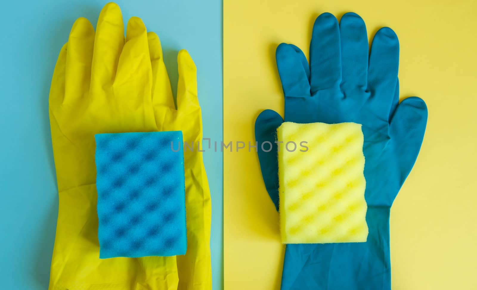Professional house cleaning concept, spring cleaning accessories, two pairs of rubber gloves and sponges on double yellow-blue background, flat lay.