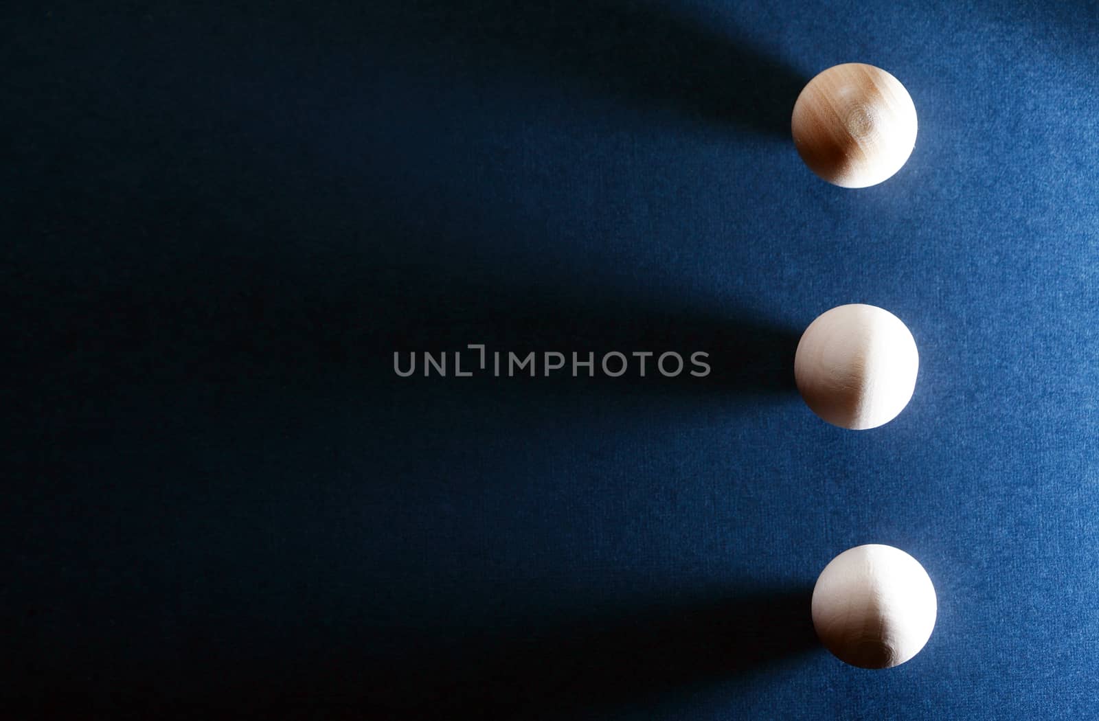 Abstract composition with three small wooden balls on dark blue background