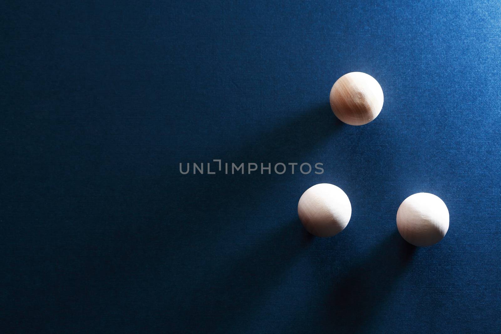 Abstract composition with three small wooden balls on dark blue background