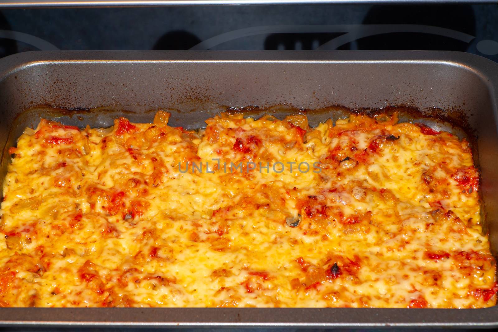 Freshly baked fish, meat and vegetable casserole with tomatoes and cheese.