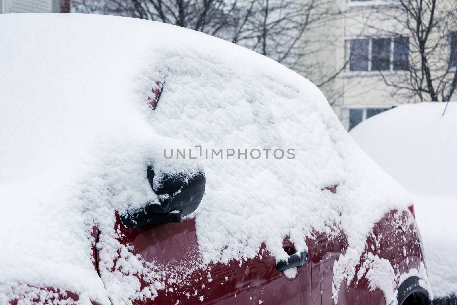 Snowfall in the city, part of the car covered by snow.