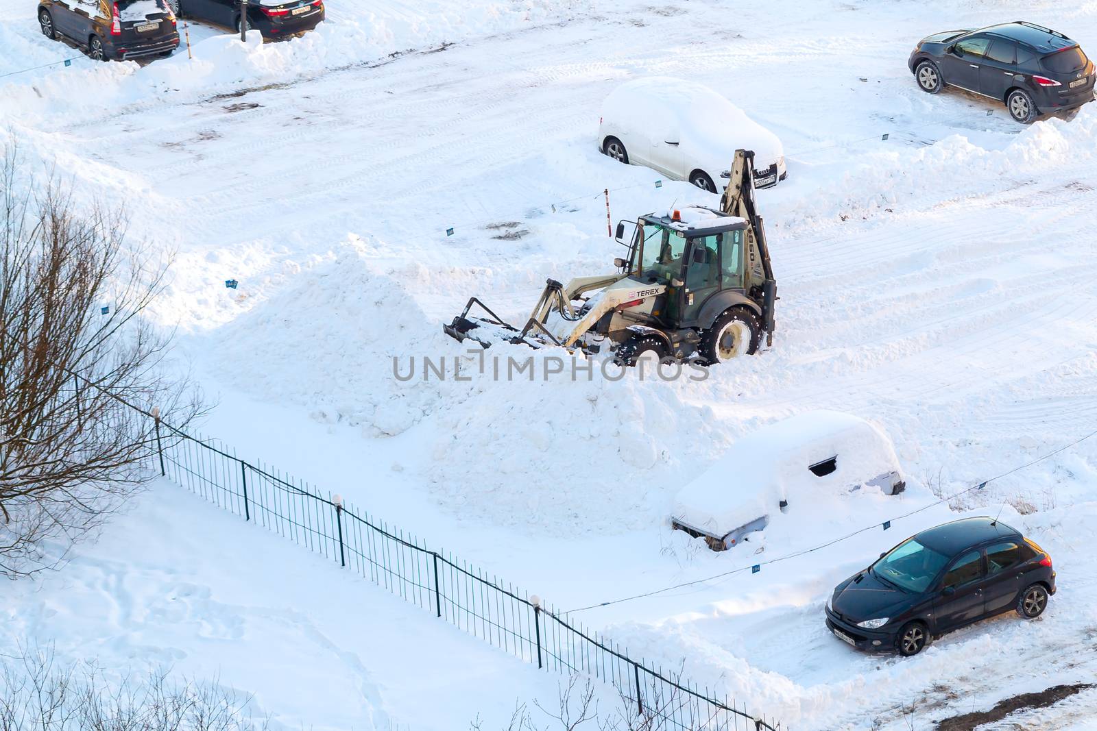 Tractor removes snow in the parking lot after a snowfall by galsand