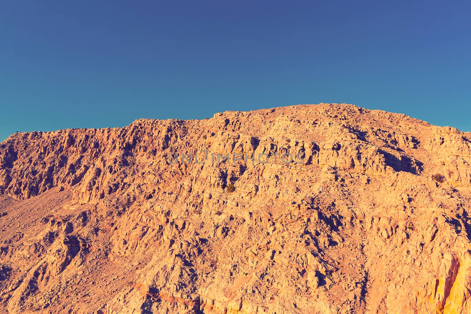 Yellow steep cliffs against the blue sky on the coast of the Arabian Sea.