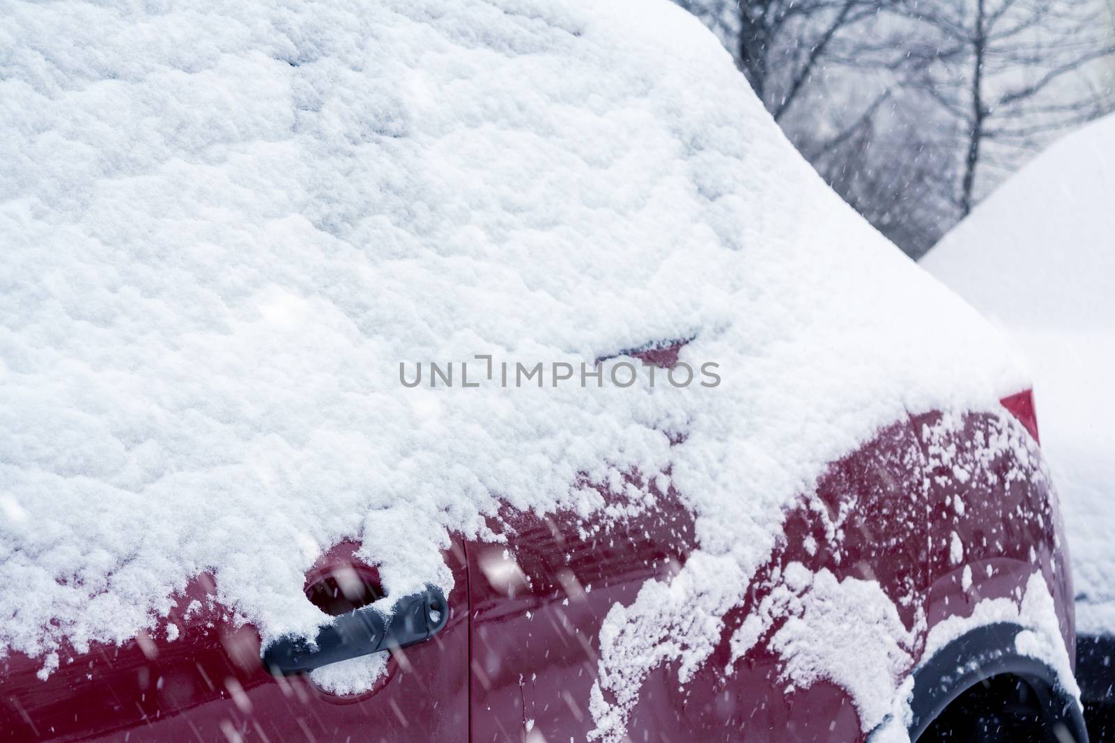 Snowfall in the city, part of the car covered by snow.