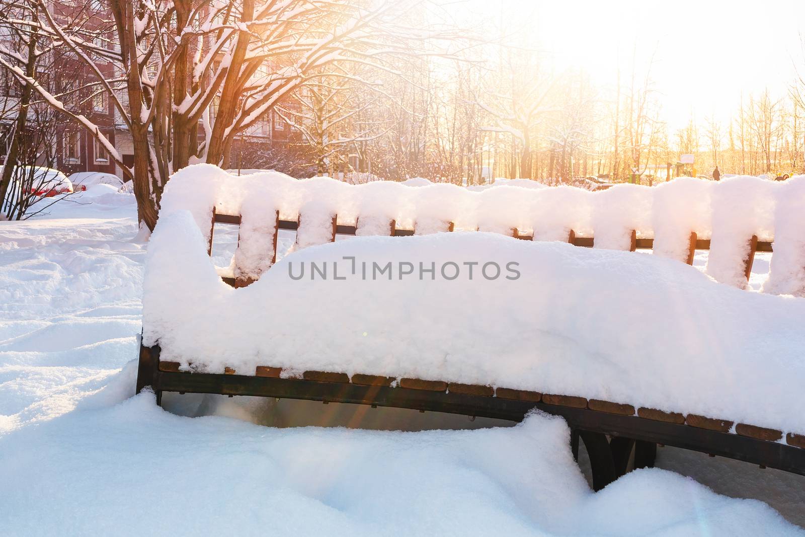 Empty wooden snow covered bench in the town square by galsand