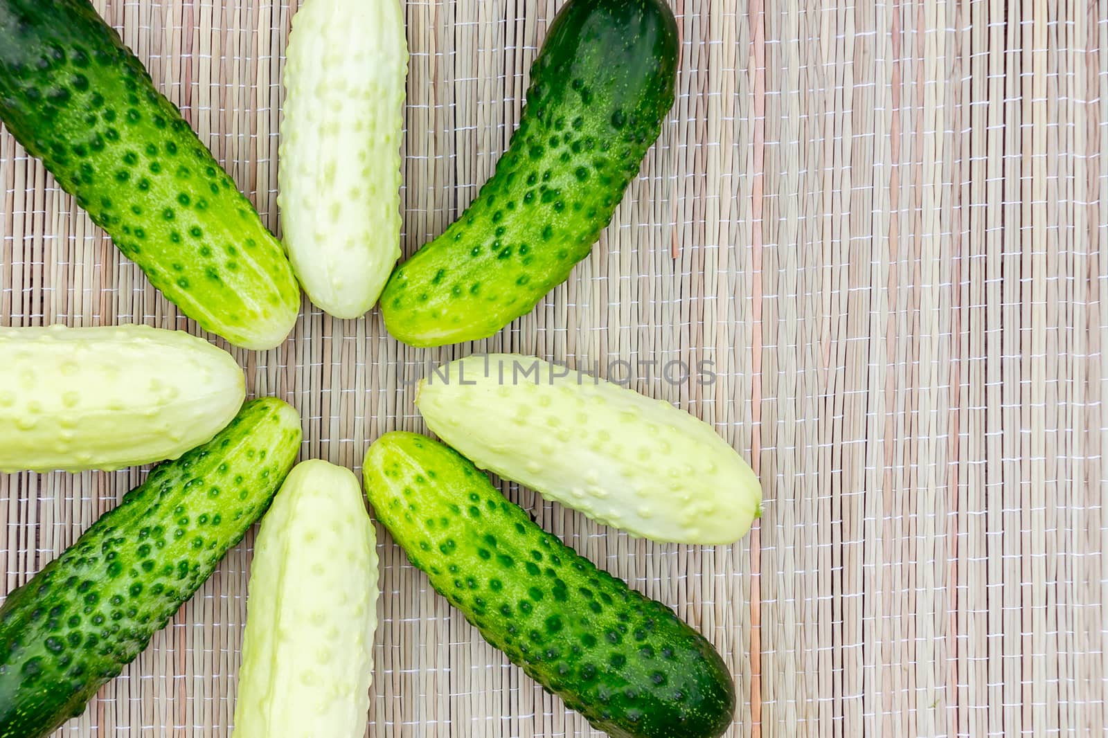 Several small star shaped cucumbers of different varieties on a wicker napkin.