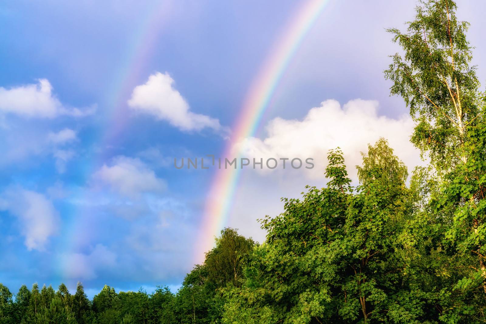 Rainbow after rain in a cloudy sky among clouds.