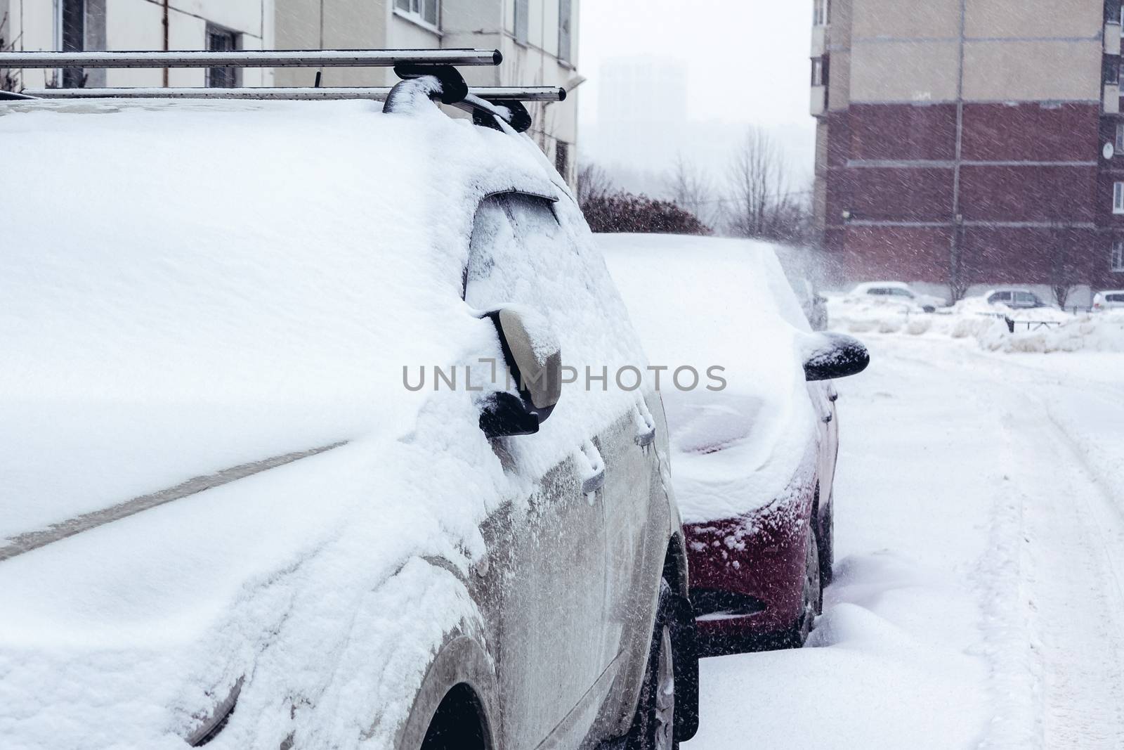 Snowfall in the city, cars overwhelmed with snow.