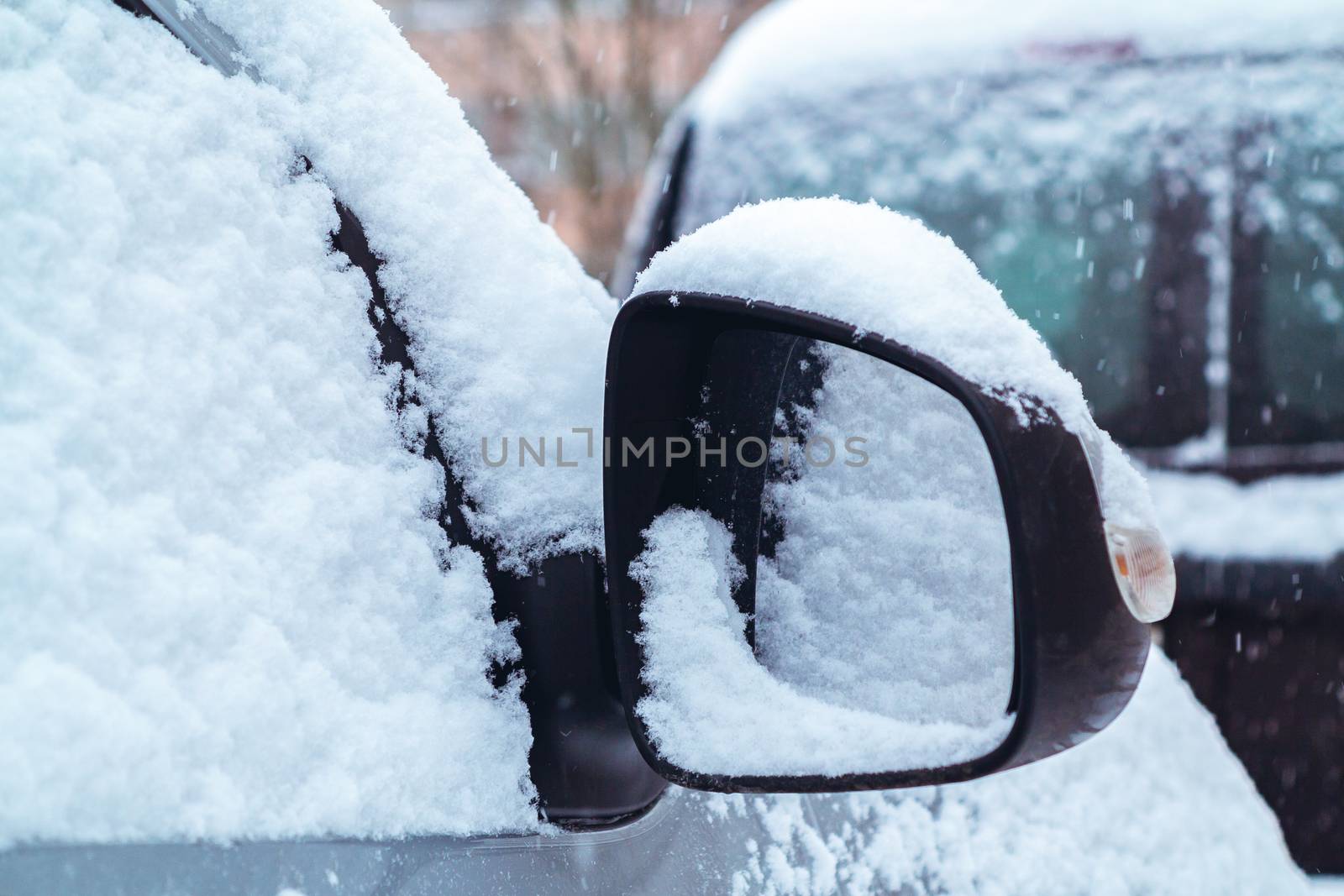 Snowfall in the city, part of the car covered by snow.