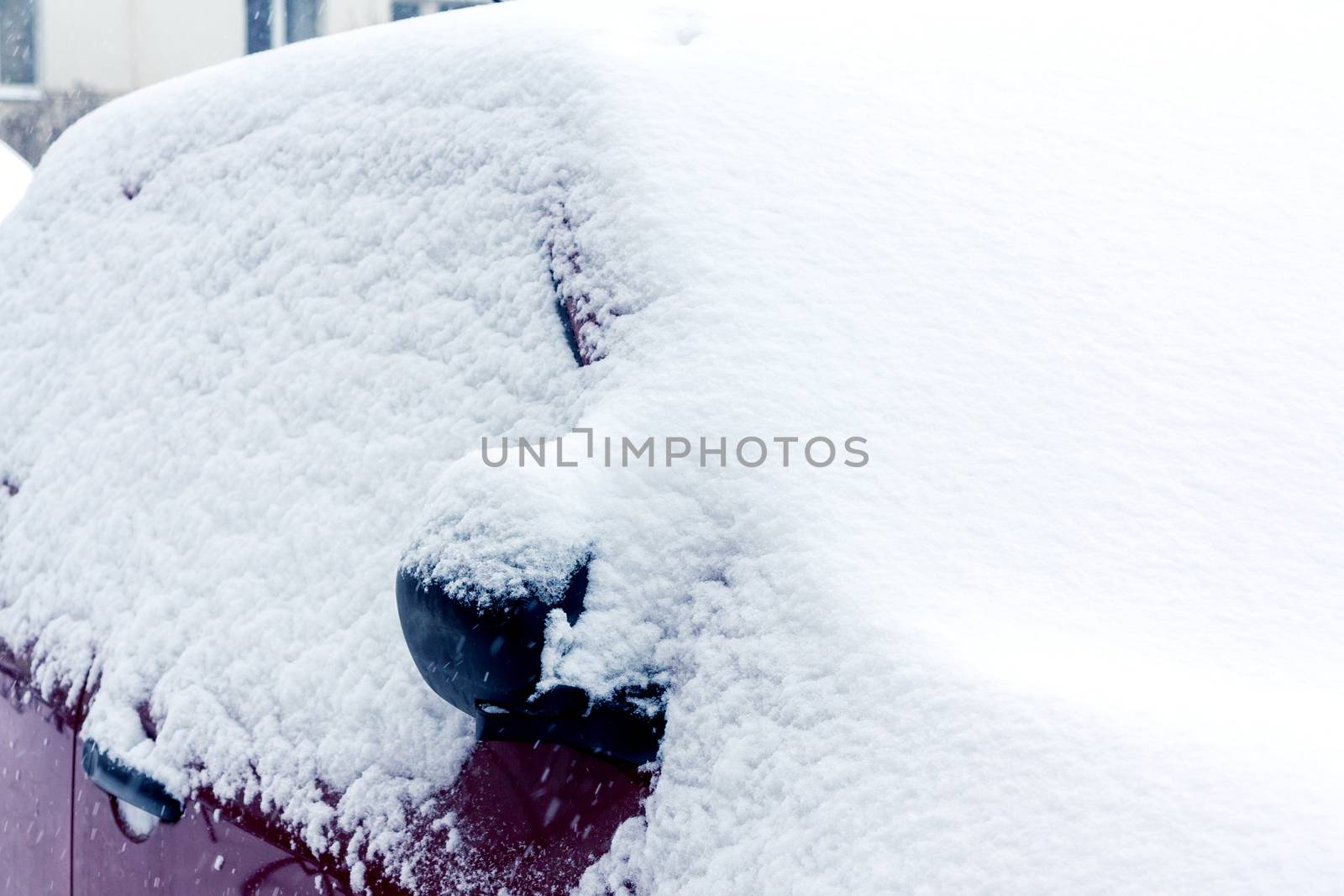 Snowfall in the city, part of the car covered by snow.