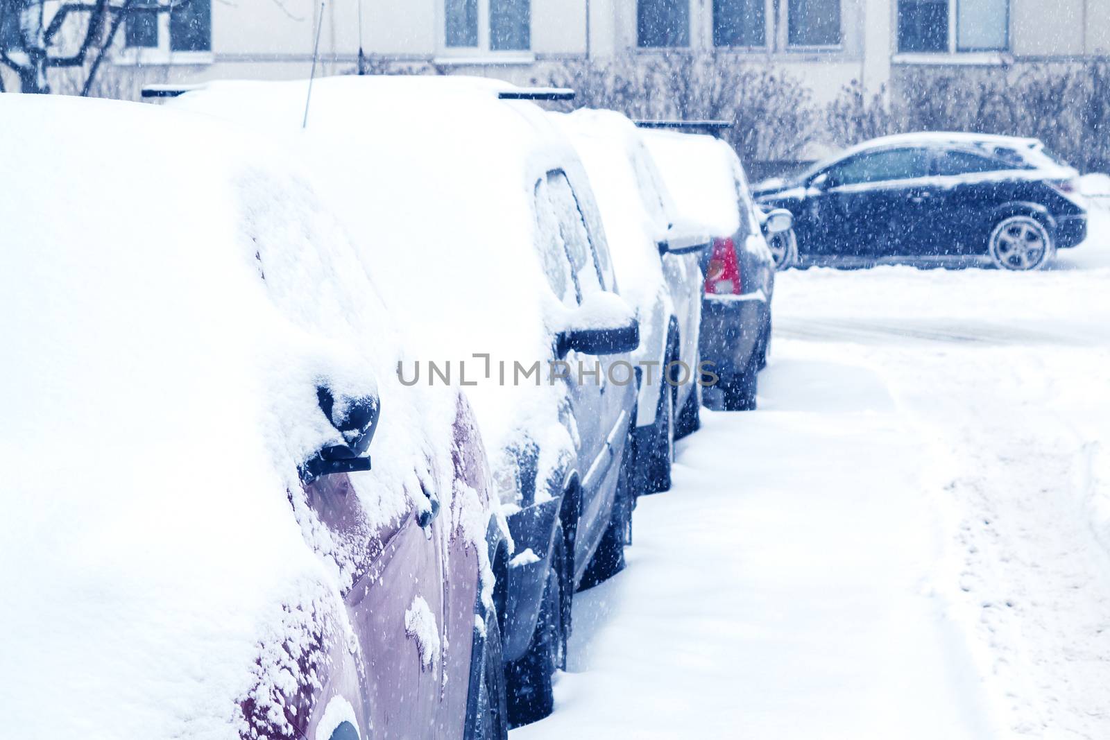 Snowfall in the city, cars overwhelmed with snow.