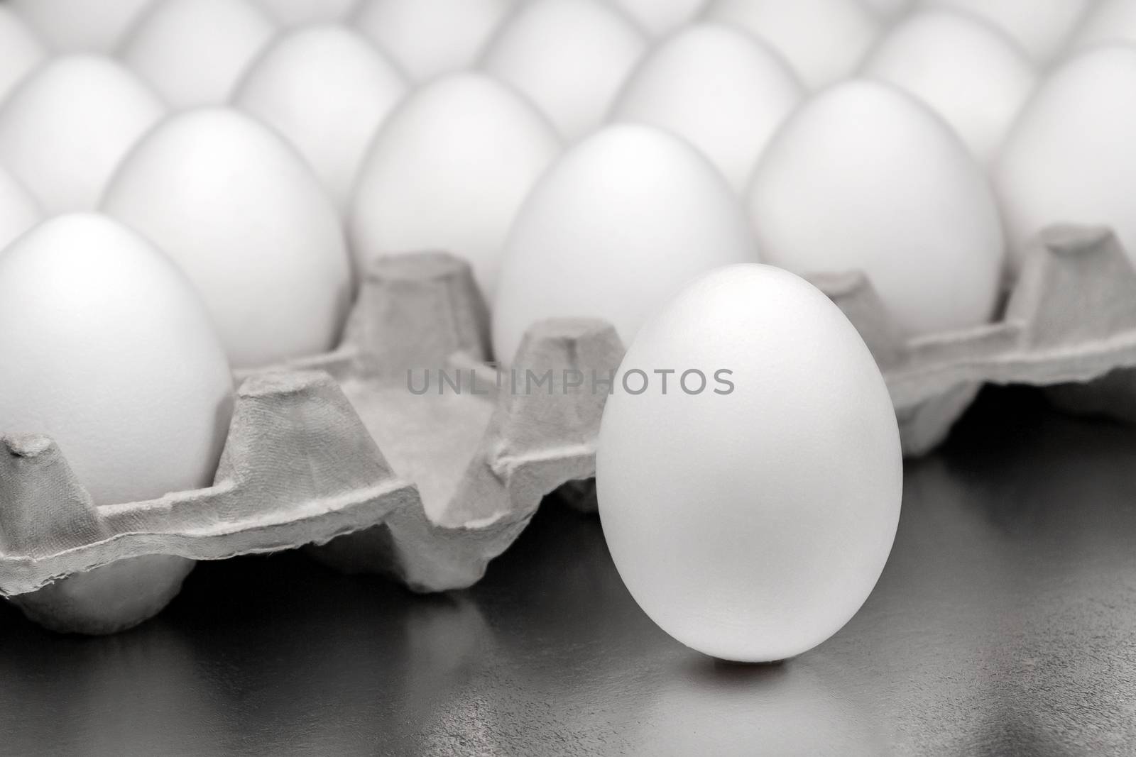 box of chicken eggs, one egg is outside the box - identity, otherness or separation concept by galsand