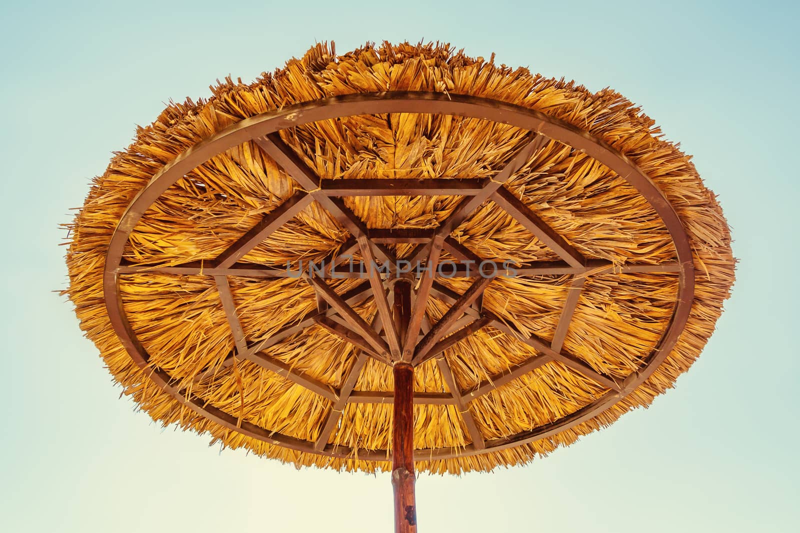 Beach umbrella made of straw against the blue sky.