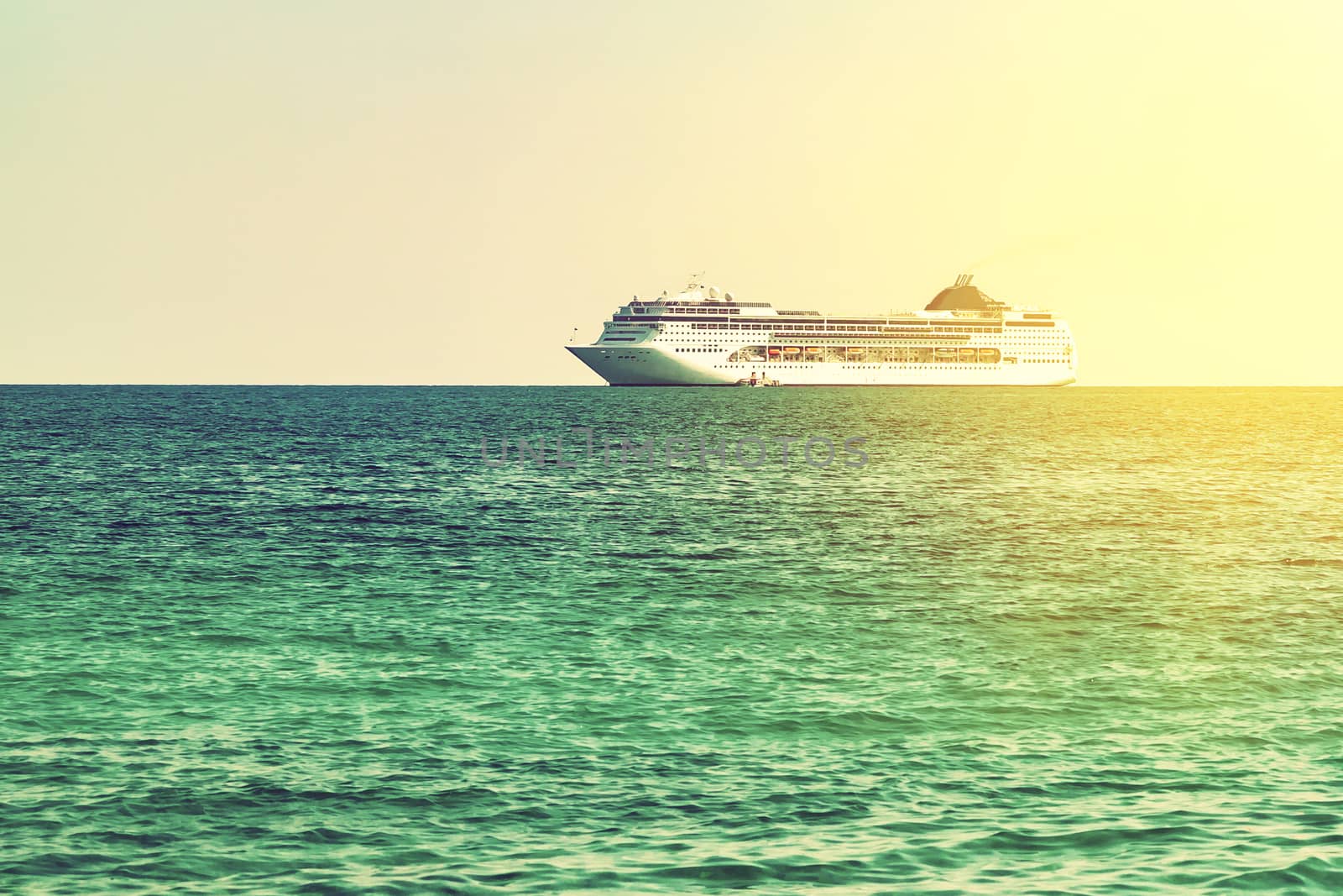 Turquoise sea with light ripples on the water and a large cruise liner on the horizon.