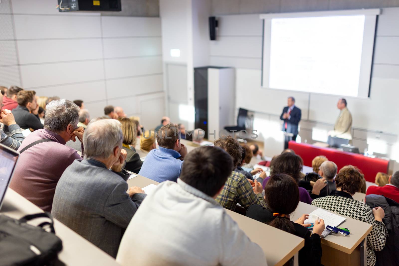 Speaker giving a talk in conference hall at business event. Audience at the conference hall. Business and Entrepreneurship concept. Focus on unrecognizable people in audience.