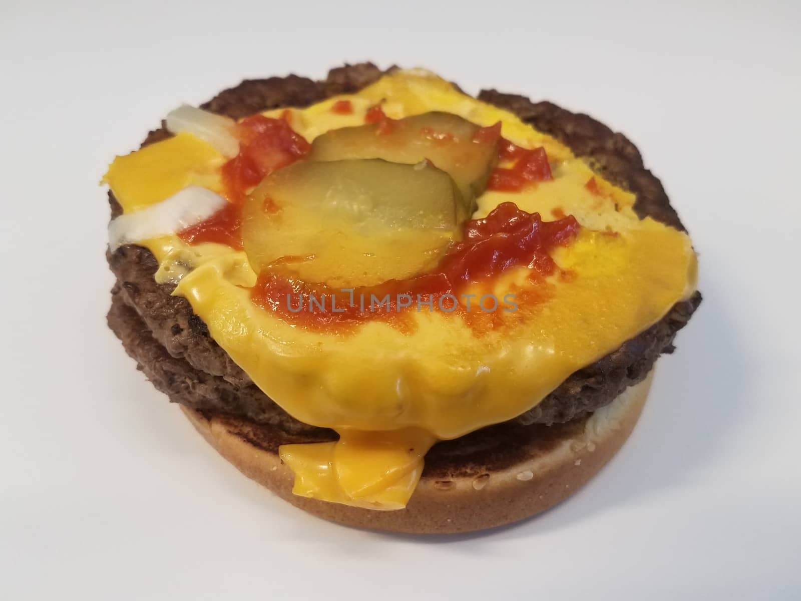 hamburger with cheese and pickles and ketchup and onions on white surface