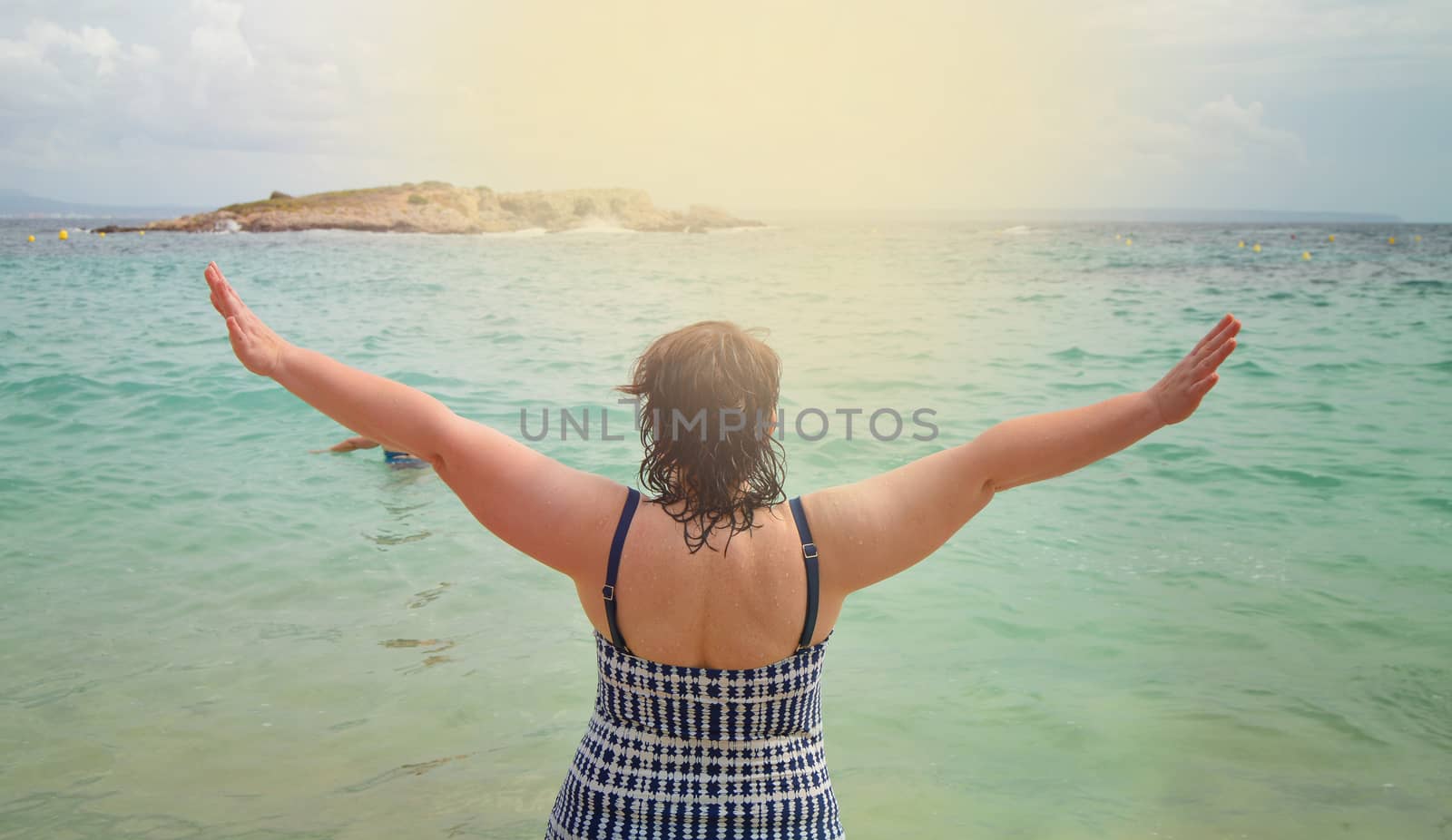 Hi summer, Happy young woman in swimsuit with her hands up, enjoying the sunrise on the sea. The view from the back, the Concept of a beach summer vacation