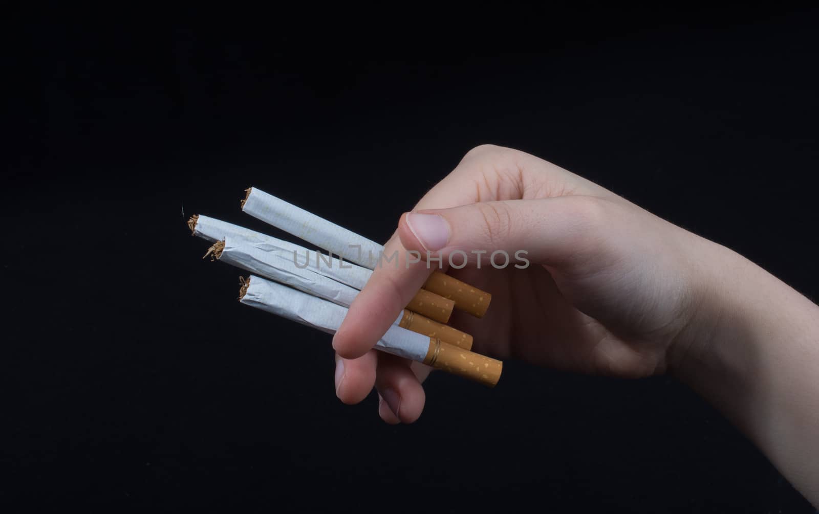 Hand is holding cigarettes on black background