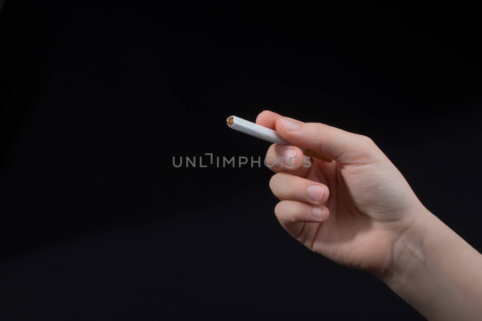 Hand is holding a cigarette on black background