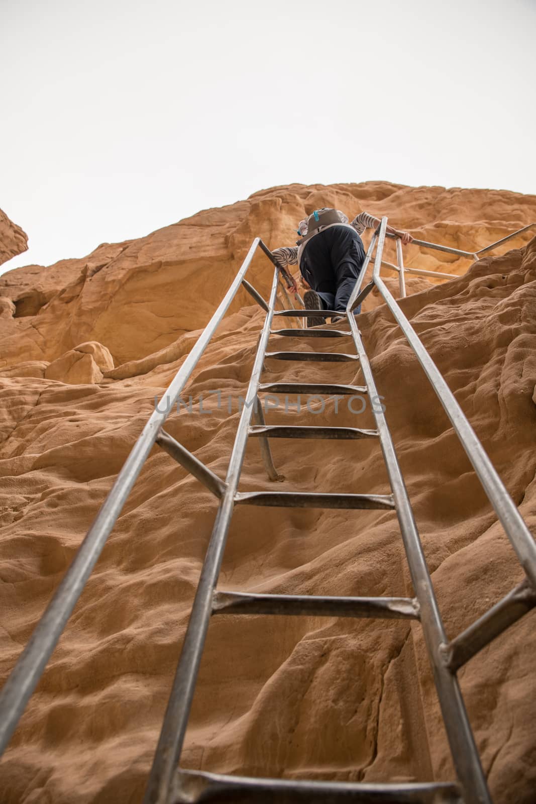 woman climbs a ladder at the arches rock in timna national park in south israel near Eilta