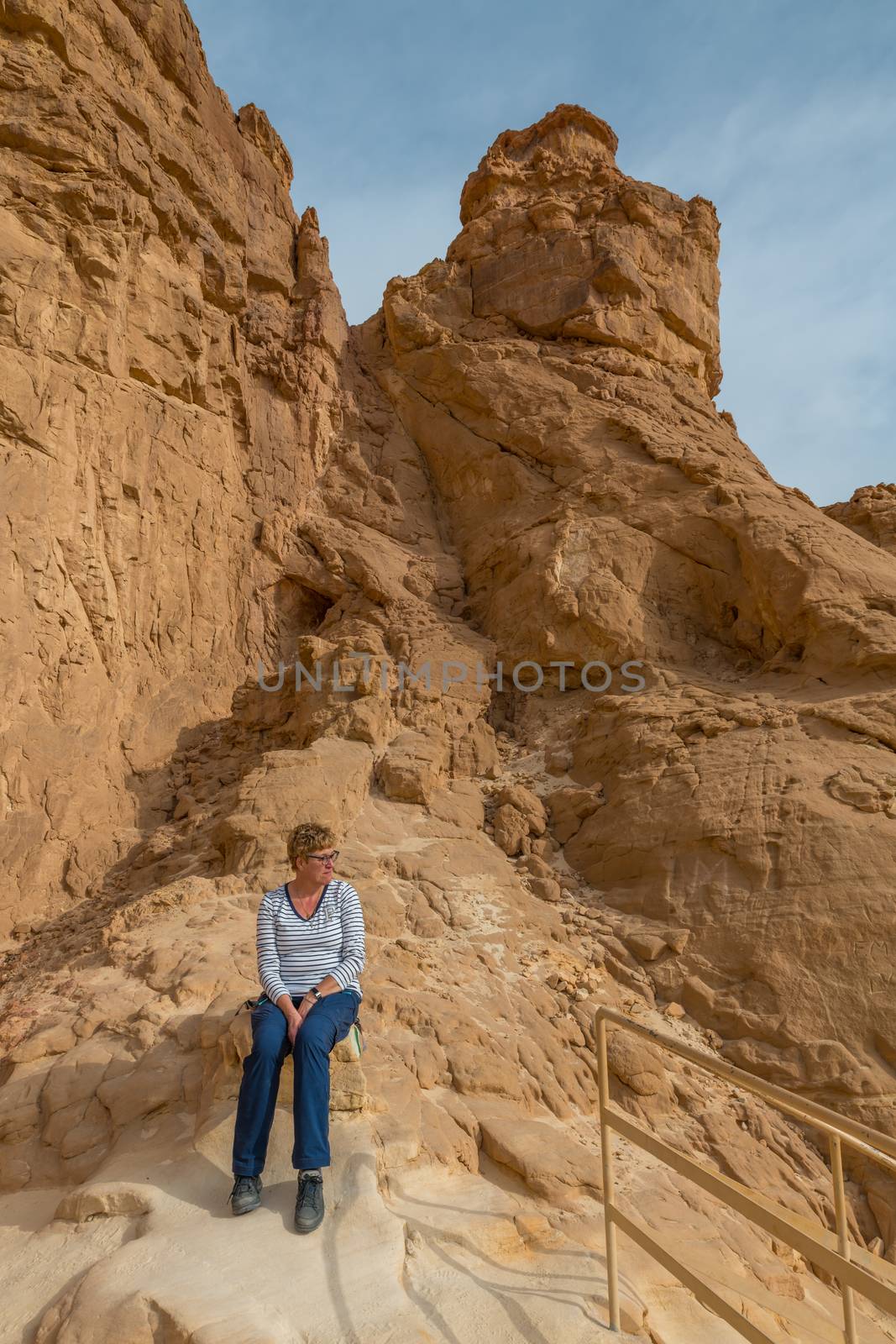 woman sitting on the rocks at the arches rock in timna national park in south israel near Eilta